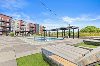A pool area with a striped sun lounger and a building in the background.